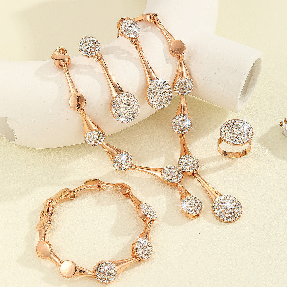 Elegant rose gold crystal jewelry collection with matching necklace, bracelet, earrings, and ring displayed on a soft ivory background with sparkling gemstone details