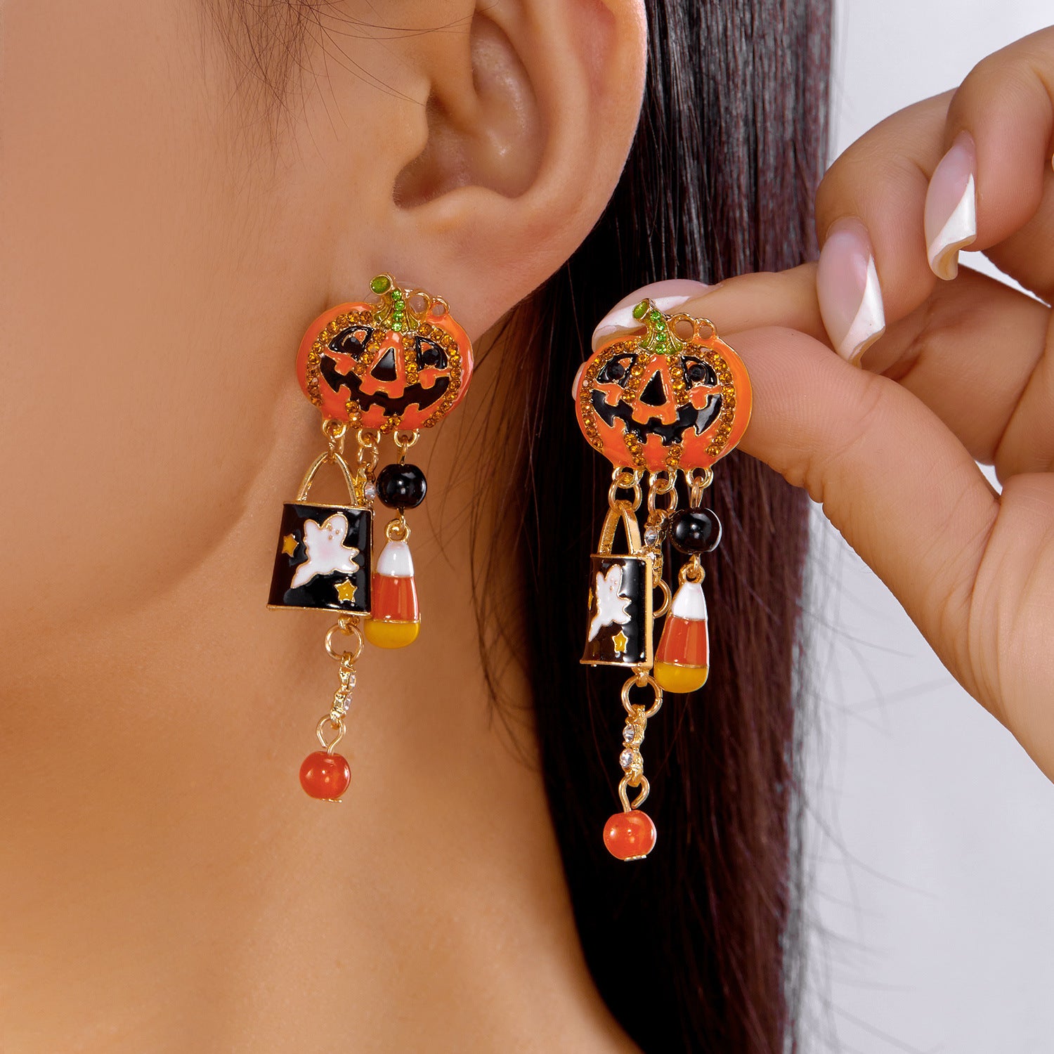 Halloween-themed earrings with jack-o'-lantern design worn by a person.