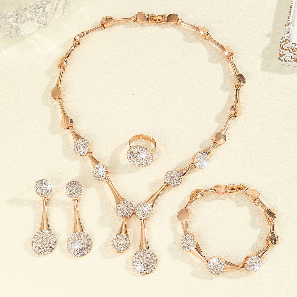 Luxury rose gold crystal jewelry set featuring a necklace, earrings, bracelet, and ring with sparkling rhinestone details on an elegant cream background
